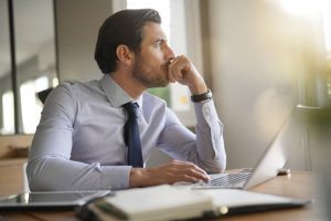 Homem de negócios concentrado em sua mesa enquanto pensa e usa um laptop