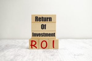 Placa de madeira com os dizeres Return of investment ROI, que avalia o retorno sobre treinamento corporativo