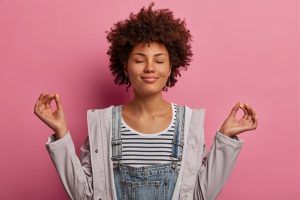 Mulher com expressão leve em fundo rosa denotando boa saúde emocional