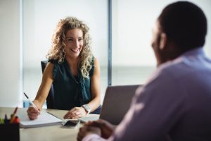 Mulher faz entrevista comportamental com candidato em sua empresa