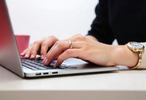 mulher digitando uma carta de apresentação, destacando suas habilidades no currículo