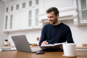 Homem recebe proposta de trabalho e a analisa do computador de sua cozinha