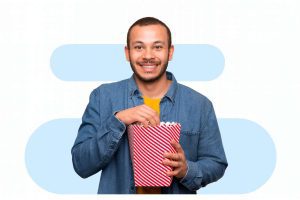 Homem sorridente segurando pacote de pipoca mostra as vantagens do ticket cultura para o engajamento