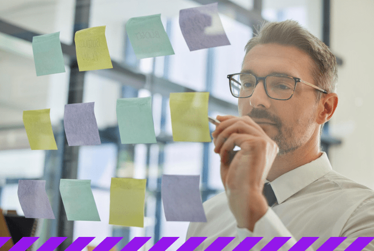 homem faz planejamento tático com post-its em painel transparente