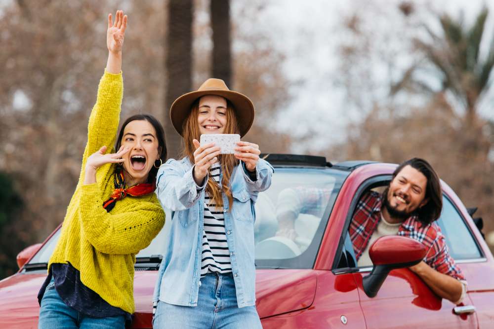 mulheres felizes fazem senfie em frente ao carro simbolizando os feriados 2025