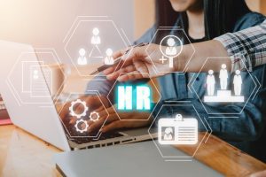 Pessoas trabalham no computador e ícones tecnológicos simbolizam a tecnologia por trás da gestão estratégica de pessoas