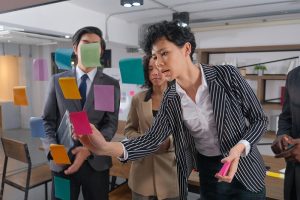 Três pessoas em uma reunião colando post its na parede