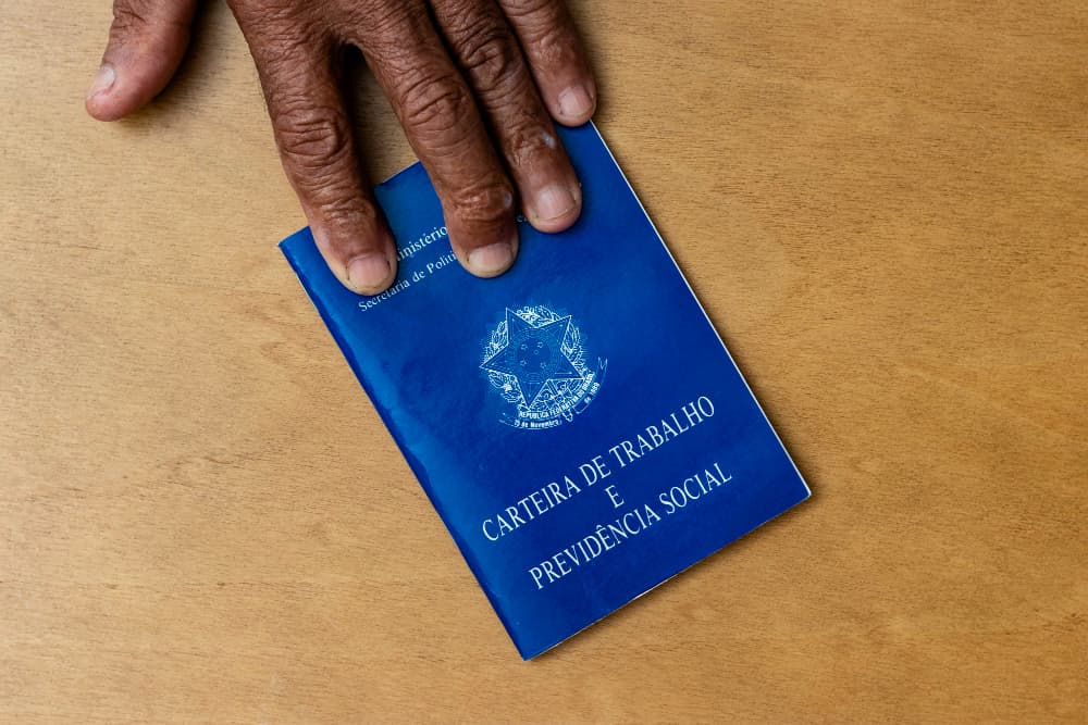 mãos segurando uma carteira de trabalho