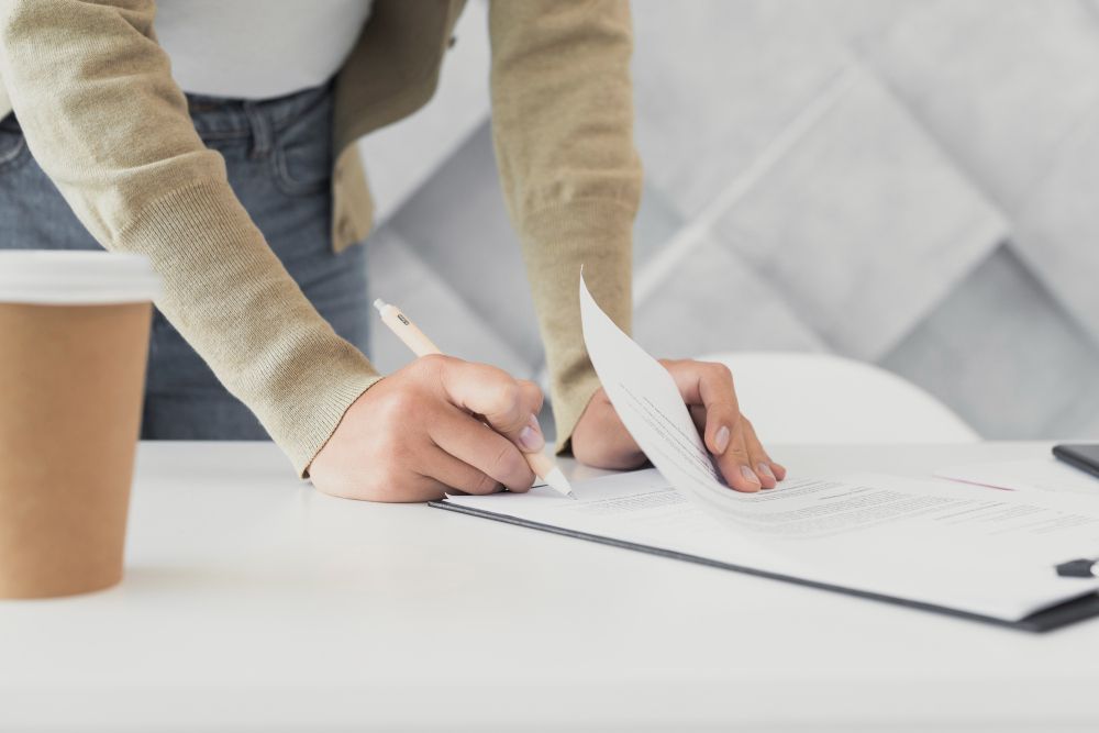 mulher assina nota promissória sobre mesa de trabalho