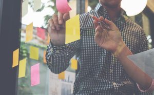 pessoa anotando em post it no vidro