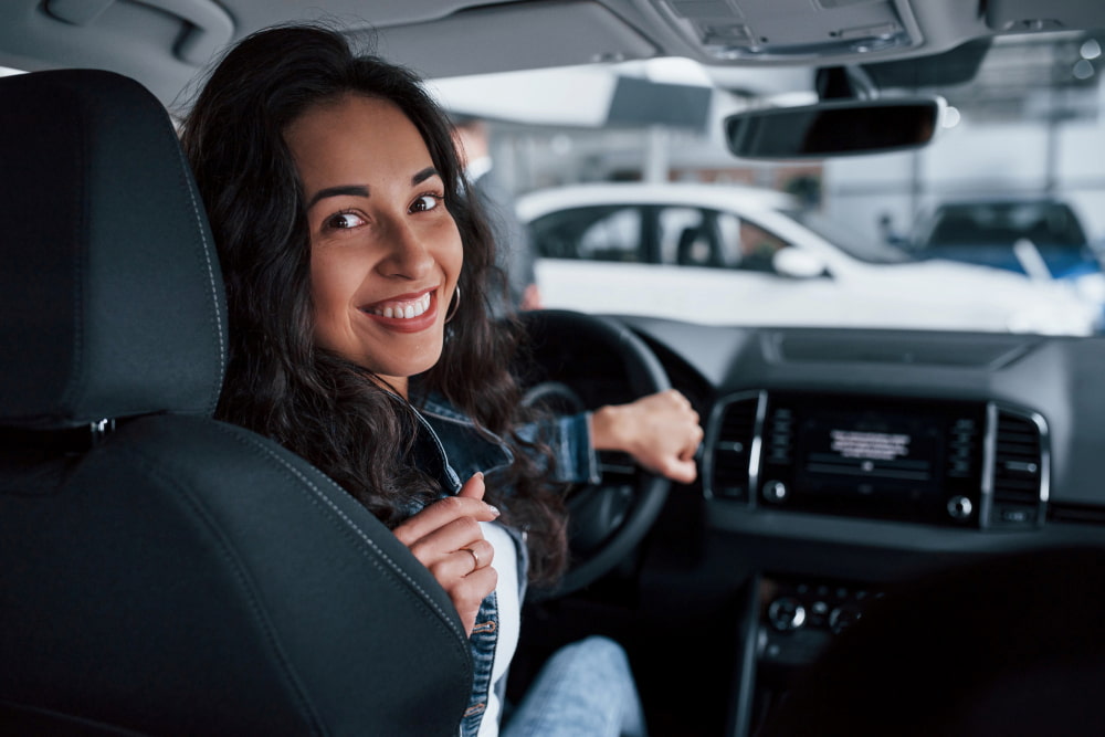 mulher sorridente sentada no banco do motorista de um carro