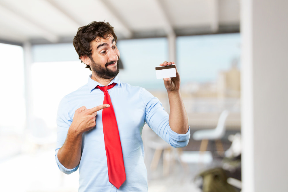 colaborador sorridente segura um cartão com a mão esquerda enquanto olha e aponta para ele com a mão direita